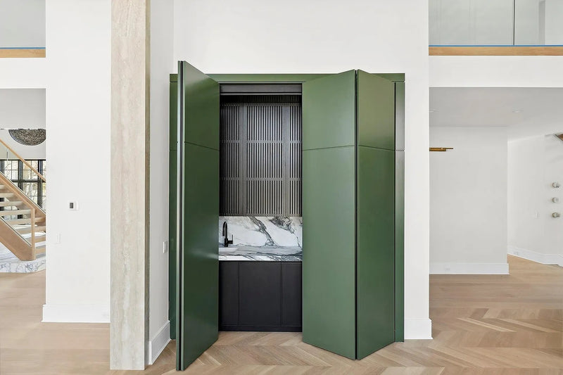 Concealed custom home bar hidden behind green cabinetry by Cambridge Kitchens.