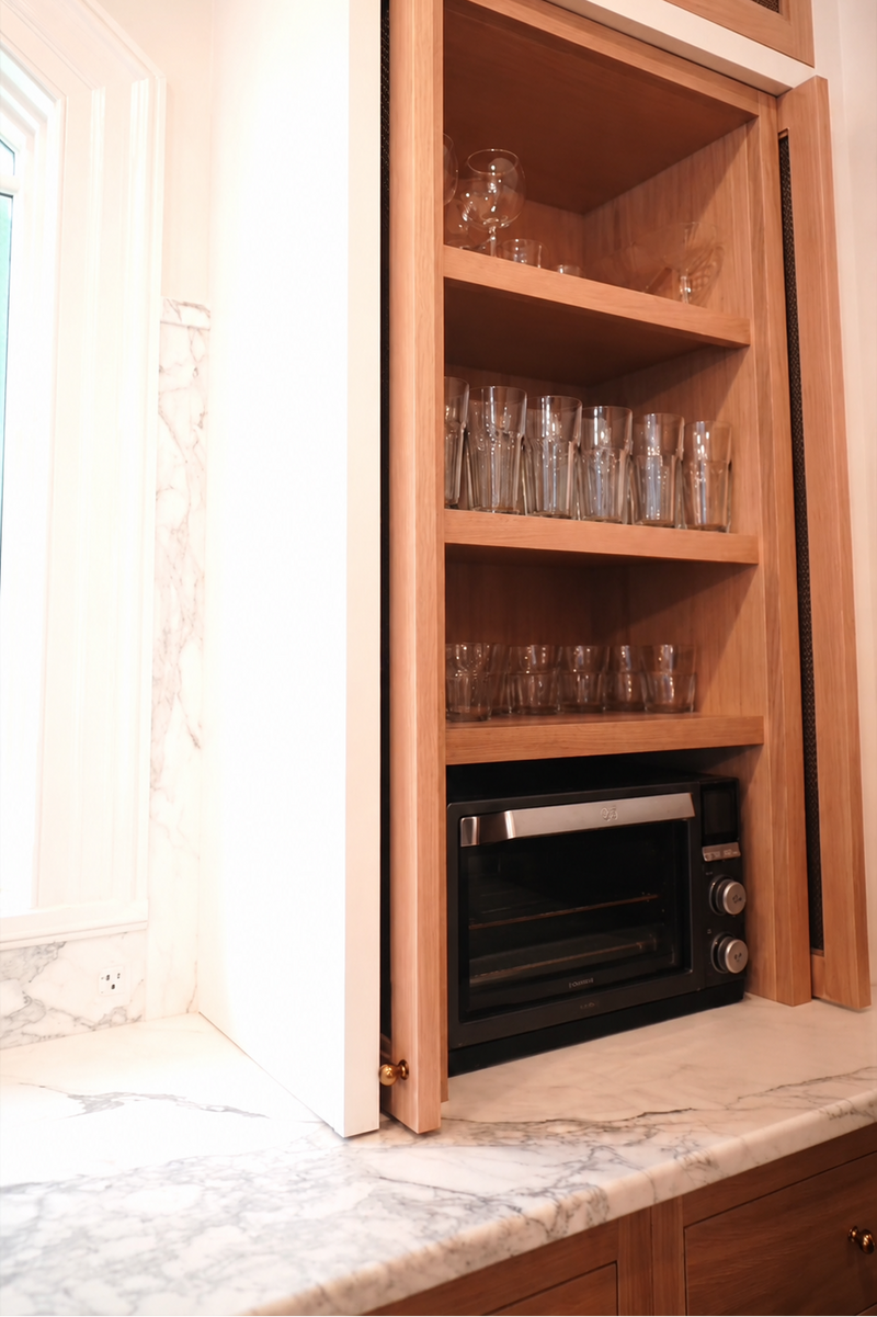 Custom appliance garage with pocket doors, wood cabinetry, integrated shelving, and concealed countertop appliance storage.