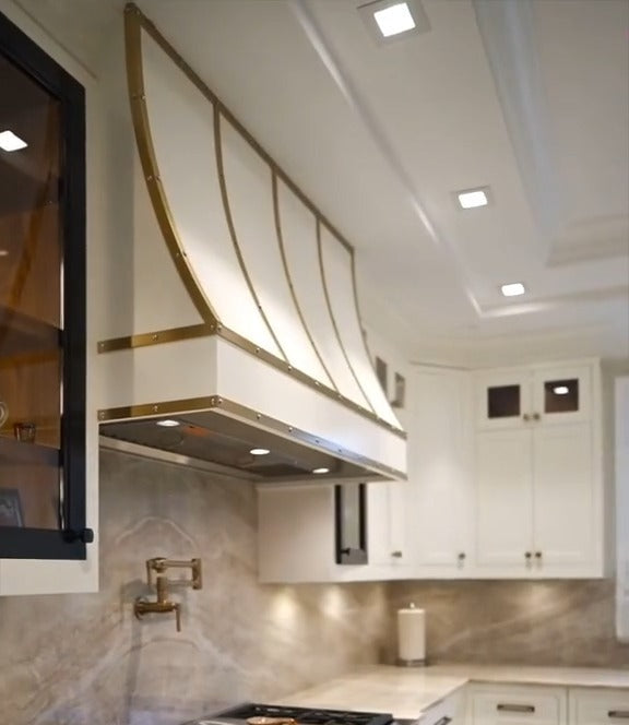Custom white kitchen range hood with brass detailing by Cambridge Kitchens.