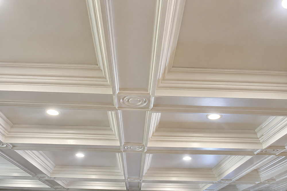 Luxury custom coffered ceiling with layered crown molding, decorative rosettes and integrated recessed lighting by Cambridge Kitchens on Long Island.