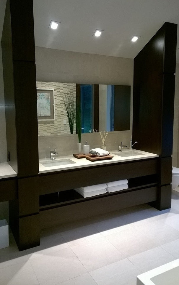 Modern custom dark wood double bathroom vanity with floor-to-ceiling cabinetry, open towel storage and integrated mirror by Cambridge Kitchens on Long Island.
